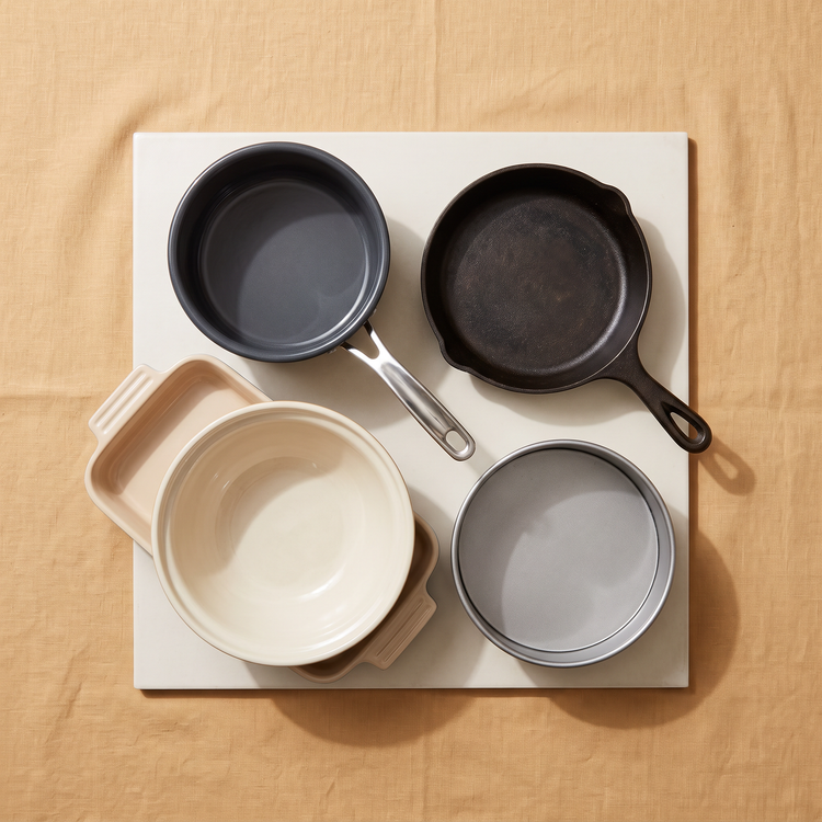 Cookware group with an enamel saucepan, cast iron skillet, mixing bowl, baking dish and cake tin