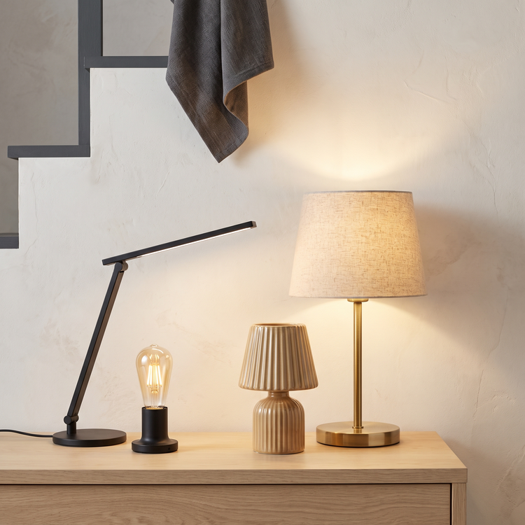 Brass table lamp, ceramic bedside lamp, LED desk lamp and smart bulb lit against a wall