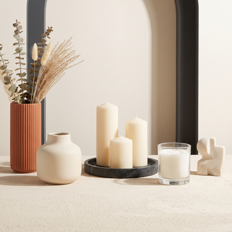 Terracotta and cream vases with pillar candles on a stone tray and a stone accent object